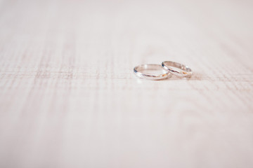Two gold rings on wooden surface. wedding rings on a light background