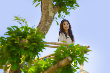 portrait of young beautiful Asian Korean woman enjoying the view from high viewpoint in a tree smiling happy and relaxed in holidays travel and excursion