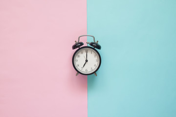 Flat lay clock on pink and blue background, Pastel colors concept