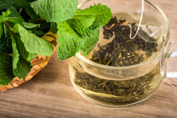 Close up a glass cup of mint tea with green fresh peppermint leaves , relaxation and healthy drink