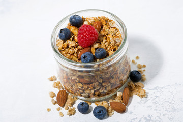 homemade muesli in a glass jar on a white background for healthy breakfast, top view