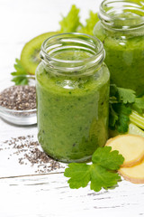 healthy green fruit and vegetable smoothies in jars on white table, vertical