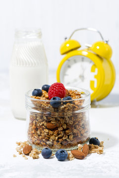 homemade muesli in a glass jar on a white background for healthy breakfast, vertical