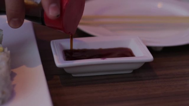 https://asn.ftcdn.net/jpg/02/04/84/77/220_F_204847706_5fXCECPvmqp2pIbnnyxU8pppzDsklhdg.jpgPouring soy sauce into a small dish at a Japanese sushi bar. Authentic Asian food cuisine. 