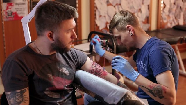 A professional tattoo artist makes a tattoo of brutal bearded men.