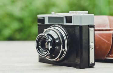 Old film camera on the background of the spring garden. Retro Photo