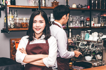 Portrait of woman barista smiling and standing behind the counter bar in a cafe