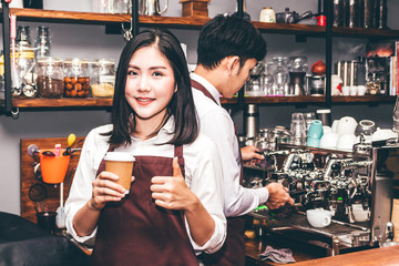 Woman barista giving coffee cup to customer at cafe