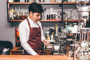 Man Barista using coffee machine for making coffee in the cafe