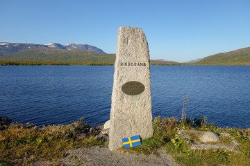 Stone marking the border crossing between Sweden and Norway at E12 road to Mo I Rana. Umbukta lake in the back