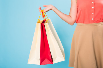 Close up of woman with colored shopping bags over blue background
