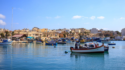 Fototapeta na wymiar Marsaxlokk historic port full of boats in Malta. Blue sky and village background.