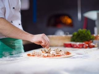chef putting fresh mushrooms on pizza dough