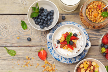 Bowl of homemade granola with yogurt and fresh berries on wooden background