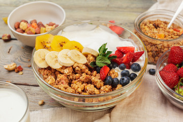 Bowl of homemade granola with yogurt and fresh berries on wooden background