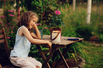 happy romantic child girl dreaming in evening summer garden decorated with candle holder.