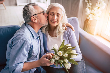 The elderly man and a woman with flowers kissing