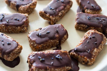 Raw vegan chocolate energy bars. Dates, nuts, cocoa, honey. Served on white plate.