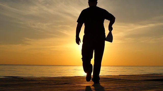 walking man throws a contract away near seashore silhouette slow motion - freedom concept