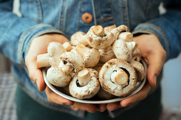 Woman hands holds raw white champignons. Organic natural permaculture farm product. Vegan, vegetarian healthy food concept.