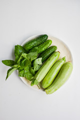 Fresh green vegetables on plate. Cucumber, zucchini, basil leaves.