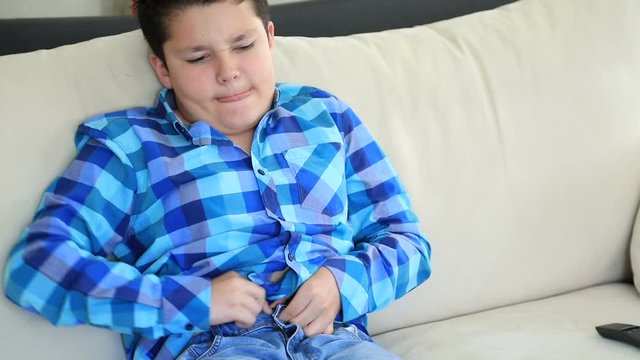 Portrait of a sad fat yung boy trying to wearing his narrow jeans