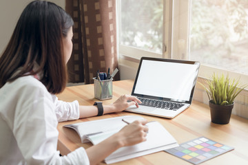 Businesswoman in office in casual shirt. Use computer for graphic designer and choose a color sample to match the publication.