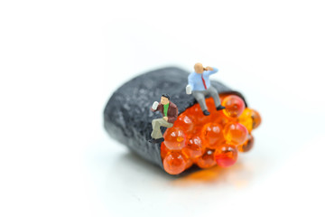 Miniature people : businessman sitting with Salmon egg on sushi nigiri roll , Food business concept.