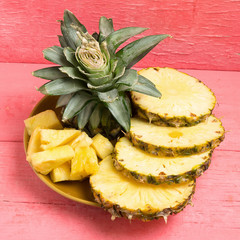 pineapple on dish slice on pink wood