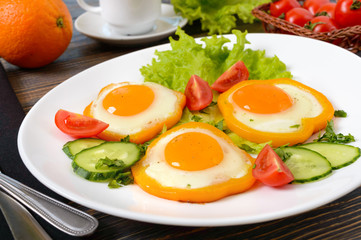 Fried egg in a circle of sweet pepper on a white plate with fresh vegetables, a cup of coffee, fresh oranges on a wooden background. Delicious healthy breakfast. Proper nutrition.