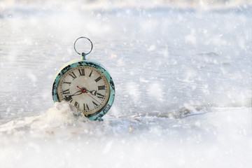 Snow falling on an alarm clock  an ice covered lake