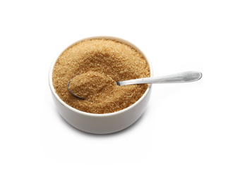 Brown cane sugar in porcelain bowl with metal spoon isolated on white background, sugarcane texture