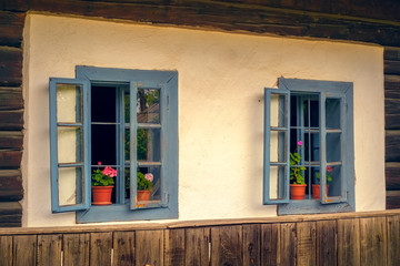 Romanian traditional wooden house with old blue windows and flowers