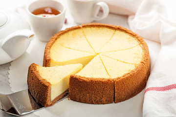 Classic New York Cheesecake and tea on light gray background.