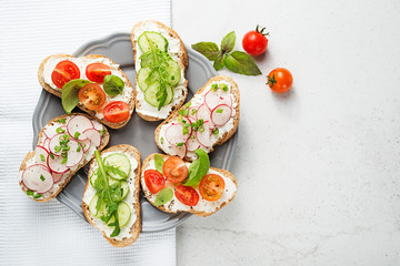 Different sandwiches with vegetables on a light gray background. top view.