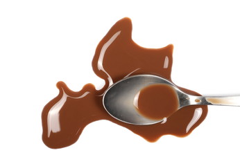 Spilled chocolate milk puddle and metal spoon isolated on white background, top view