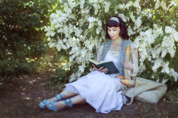 Young woman sits near a bush.