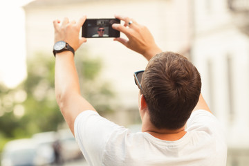 Man doing a selfie with smart phone outdoors.