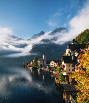 Scenic view of famous Hallstatt lakeside town reflecting in Hallstattersee lake in the Austrian Alps in morning light with bright clouds, Salzkammergut region, Austria