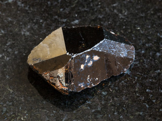 rough crystal of Cassiterite stone on black