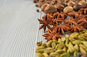 Fototapeta na wymiar Aromatic Indian spices on the gray kitchen table: star anise, nutmeg, cardamom close up. Spices texture background with free copy space. Ingredients for spicy food. Side view