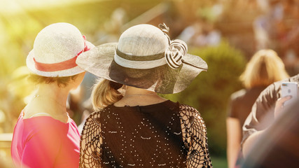 Ladies with hats on the race track. Romantic summer hats. Retro style summer romance.