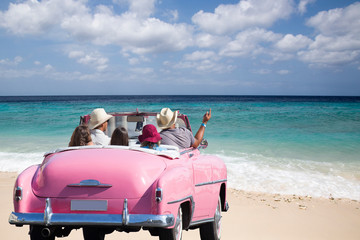 Fröhliche Freunde in traumhaftem Oldtimer (Cabriolet) am kubanischen Strand