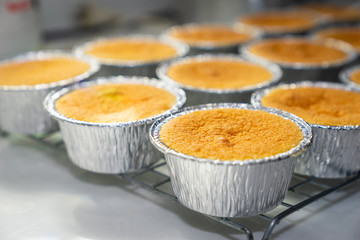 Close up to homemage butterscotch cupcakes in foil cup placed on steel grating that just removed from the oven.