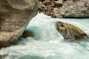 Rapid flow of water against the background of large stones.