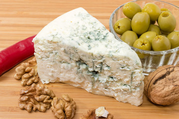 Blue cheese among of green olives, chili and walnuts closeup