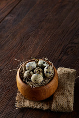 Rustic still life with quail eggs in bucket, box and bowl on a linen napkin over wooden background, selective focus