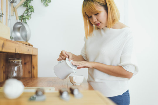 Attractive beautiful asian woman enjoying warm coffee in the kitchen at her home. Asian female wearing comfortable sweater holding a cup of coffee. lifestyle asia woman at home concept.
