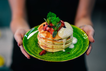 Pancakes with strawberries and cream. On a black wooden background. Copy space.