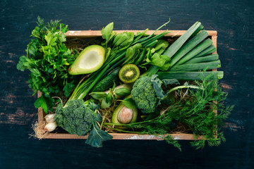 Fresh green vegetables and fruits in a wooden basket. Healthy food. Top view. Copy space.